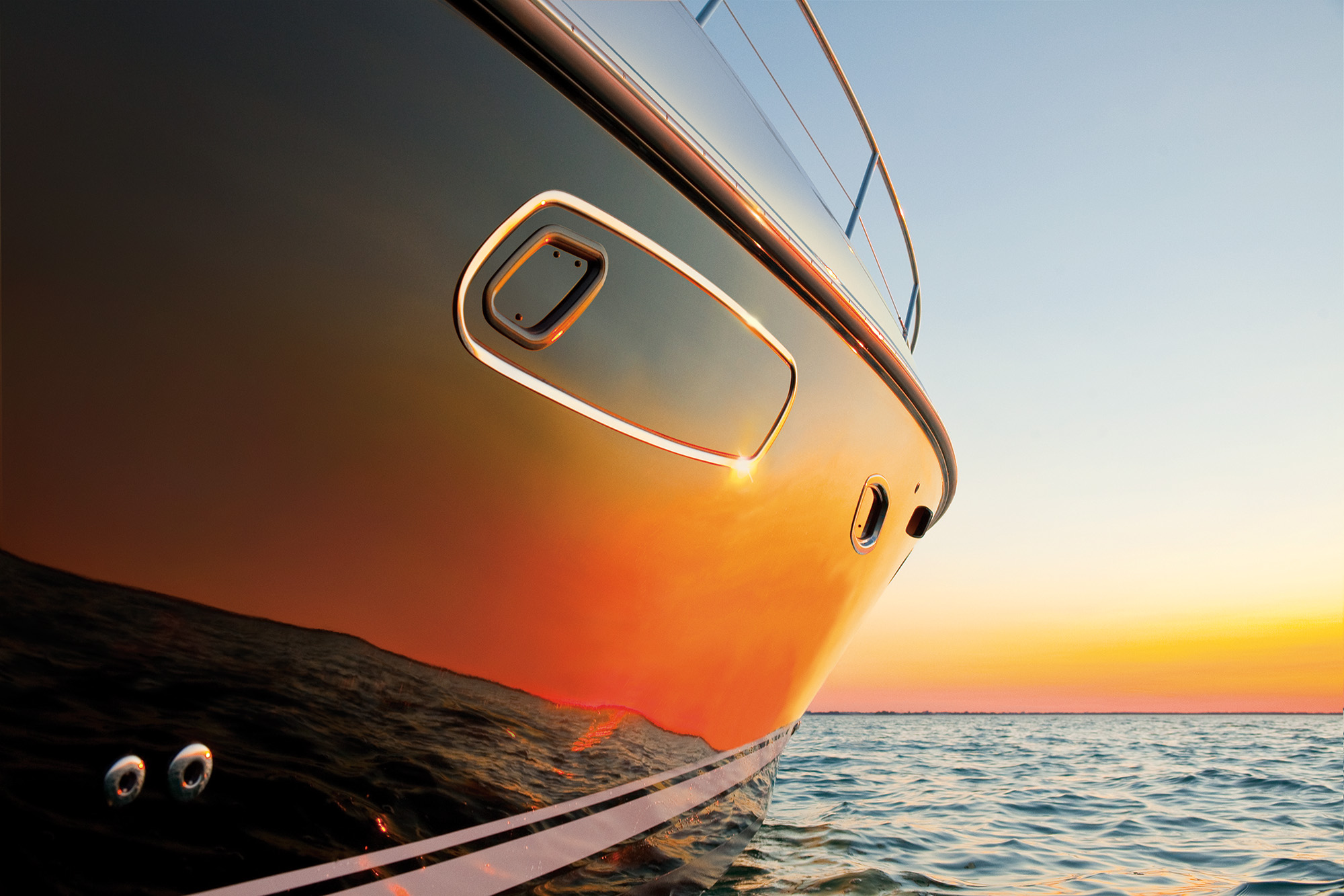 A bright orange sunset, reflected in the hull of a motorboat